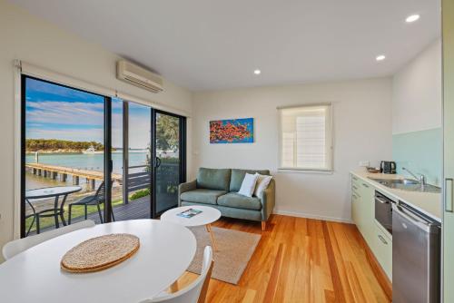 a kitchen and living room with a table and a couch at Anglesea Waterfront Bungalow in Huskisson