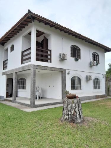 Uma casa branca com um tronco de árvore à frente. em Mansion in the mountains em Teresópolis