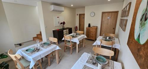 una sala da pranzo con tavoli, sedie e orologio di Casa da Maragoça a Portela