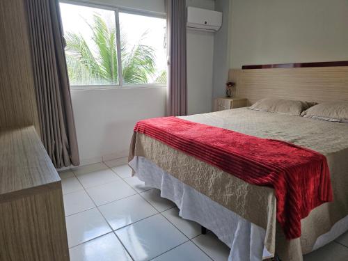 a bedroom with a bed with a red blanket on it at Frente ao Parque da Lagoa Quente Entrada NÃO INCLUSA Aptos Particulares com varanda in Caldas Novas