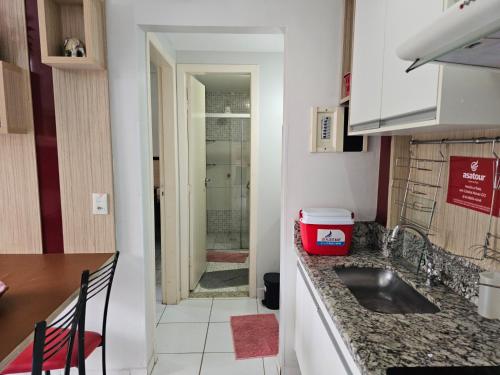 a kitchen with a sink and a door to a bathroom at Frente ao Parque da Lagoa Quente Entrada NÃO INCLUSA Aptos Particulares com varanda in Caldas Novas