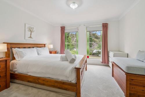 Un dormitorio con una cama grande y dos ventanas. en Minnehaha, en Katoomba