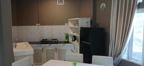 a kitchen with a black refrigerator and white cabinets at Villa Panorama Amed in Ambat