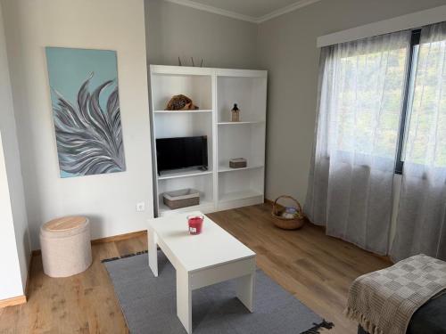 ein Wohnzimmer mit einem weißen Tisch und einem Fernseher in der Unterkunft Casa Rosa in Porto da Cruz