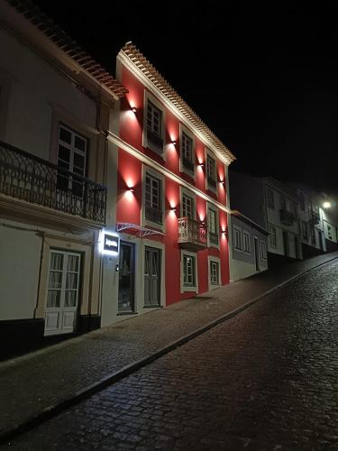 a building with red lights on a street at night at Memória Charming House in Angra do Heroísmo