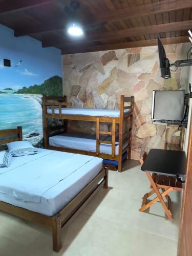 a room with two bunk beds and a tv at Guaraú Surf House Chalés in Peruíbe