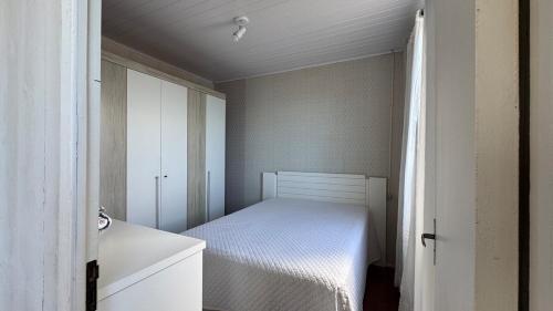 una piccola camera con letto e armadietto bianco di Recanto pé na areia a Governador Celso Ramos