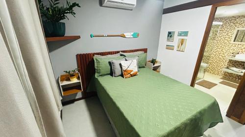 a bedroom with a bed with green sheets and pillows at JanHouse Ilhabela in Ilhabela