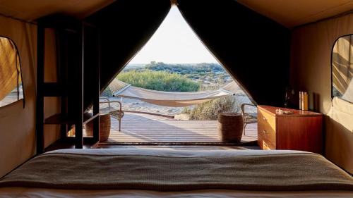 a bedroom with a bed and a view of a boardwalk at Sal Salis Ningaloo Reef in Exmouth