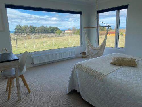 LeñaduraHermosa Casa con vista al Estrecho de Magallanes的一间卧室，配有一张床、一张书桌和一扇大窗户