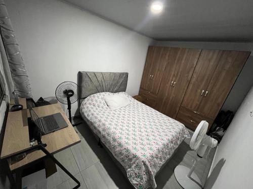 a bedroom with a bed and a desk and a laptop at Apartamento Vacacional con Piscina in Ibagué