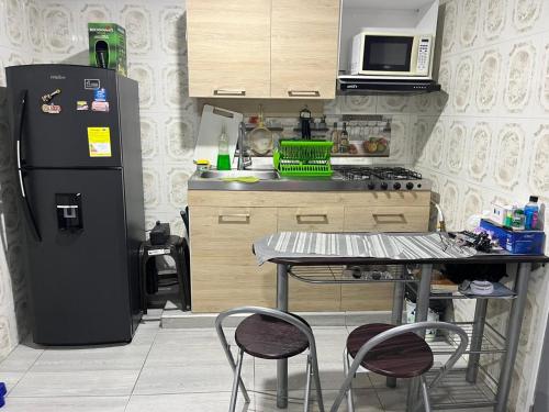 a kitchen with a refrigerator and a table with chairs at Apartamento Vacacional con Piscina in Ibagué
