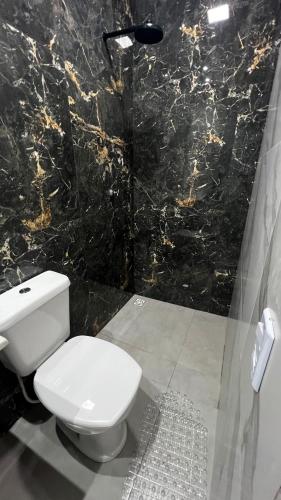 a bathroom with a white toilet and a black marble wall at Studio no Centro da Cidade in Parauapebas