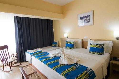 a hotel room with two beds with blue and yellow pillows at Hotel Santa Maria in Praia