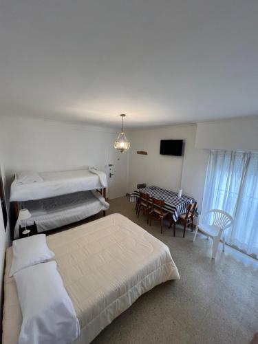 a room with three beds and a table and a television at Depto 1 ambiente frente al mar y céntrico in Mar del Plata