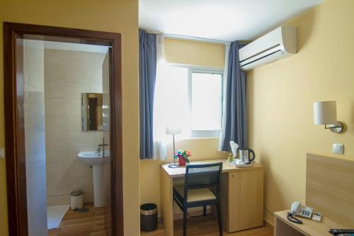 uma casa de banho com um lavatório e uma secretária com uma cadeira. em Hotel Santa Maria em Praia