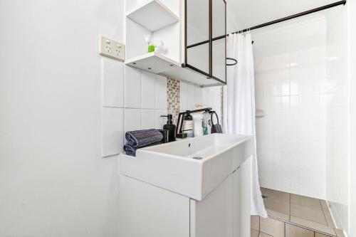 un bagno bianco con lavandino e specchio di Goulburn Stay with Garden Views & Comfort a Goulburn