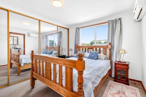 una camera con letto in legno e specchio di Goulburn Stay with Garden Views & Comfort a Goulburn