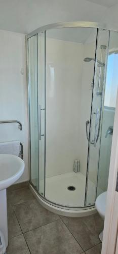 Waiheke IslandSerene One Bedroom Seaview Chalet的带玻璃淋浴和水槽的浴室