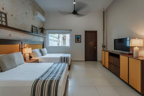 a hotel room with two beds and a flat screen tv at Espectacular casa en Progreso con alberca in Progreso
