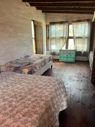 a bedroom with two beds and a dresser with a window at Cabaña Cica in Punta Del Diablo