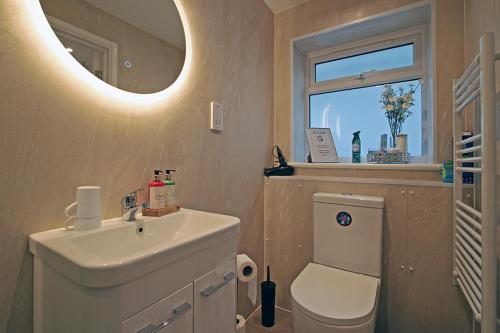 a bathroom with a sink and a toilet and a window at Cornish Dreams in Camborne