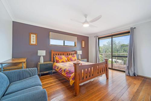 ein Schlafzimmer mit einem Bett und einer Couch in der Unterkunft The Beachfront in Lake Cathie