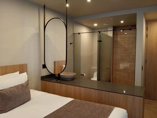 1 dormitorio con espejo grande y baño en Hotel Rulay Medellin, en Medellín