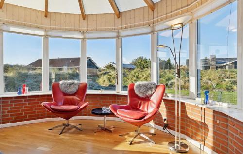 zwei Stühle und ein Tisch in einem Raum mit Fenstern in der Unterkunft Amazing Home In Ringkøbing With Sauna in Nørby