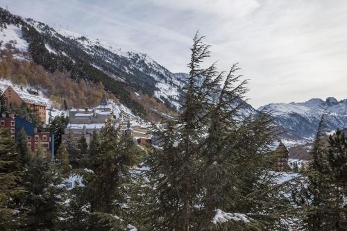 Un pueblo en las montañas con árboles y nieve. en Apartamento Familiar Baqueira 1500, en Naut Aran (Alto Arán)