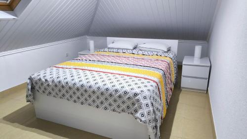 um quarto com uma cama branca e um cobertor colorido em Banda Além Apartment by Mth em Tábua