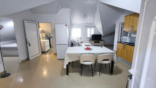 uma cozinha com uma mesa branca e cadeiras num quarto em Banda Além Apartment by Mth em Tábua