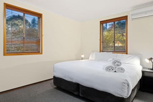 ジンダバインにあるMogul Lakeside - East Jindabyneのタオルが敷かれた白いベッドのある寝室