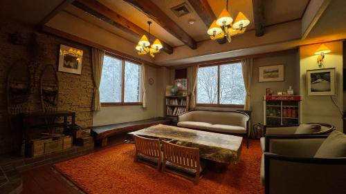 uma sala de estar com uma mesa e um sofá em 志賀 石の湯ホテル em Yamanouchi