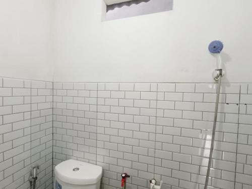 a white tiled bathroom with a toilet and a shower at Dieng Indah Villa & Cabin by Hello Room in Dieng