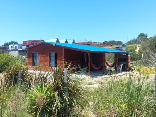 ein Haus mit einem blauen Dach auf einem Feld in der Unterkunft Cabaña Punta del Diablo in Punta Del Diablo
