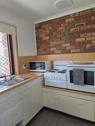 a kitchen with a stove and a brick wall at Parklands Cottage in Cowes