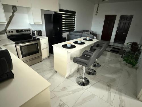 Eine Küche mit einer weißen Kochinsel mit Stühlen und einem Herd in der Unterkunft G&M Hill view Horizon in Kingston