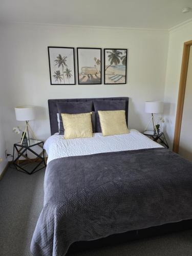 a bedroom with a large bed with three pictures on the wall at Parklands Cottage in Cowes