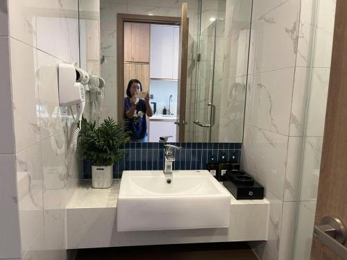 a woman taking a picture of a bathroom sink at HomeStay ICON40 HẠLONG in Ha Long