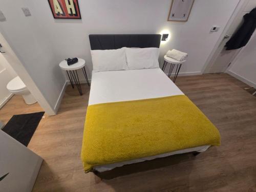 a bedroom with a large bed with a yellow blanket at Stokey Six in London