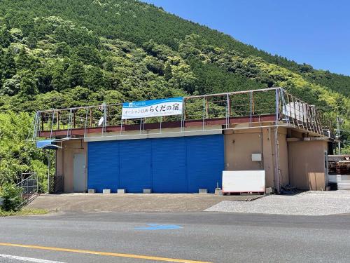 a building with a blue garage with a sign on it at オーシャン日南らくだの宿 in Nichinan