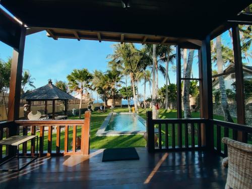 un porche con vistas a la piscina y a las palmeras en Kubu He Mamatica, en Tianyar