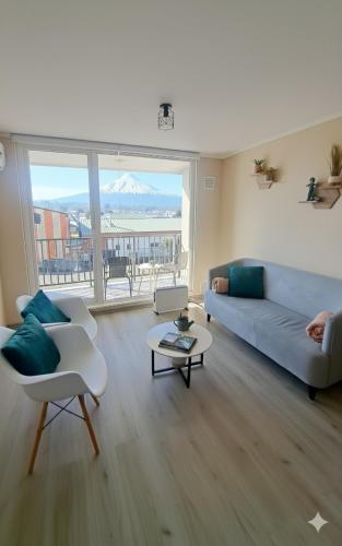 a living room with a couch and a table at Departamento con vista al Volcán in Villarrica