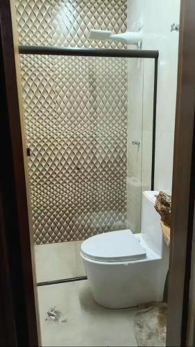 a bathroom with a toilet and a glass shower at Guaraú Surf House Chalés in Peruíbe
