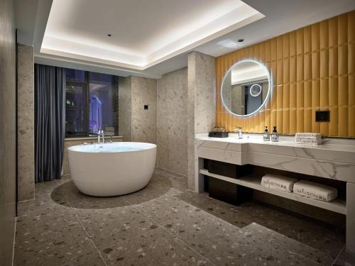 Meisu Huanman Hotel Changsha IFS Wuyi Square Branch في تشانغشا: حمام مع حوض كبير ومرآة