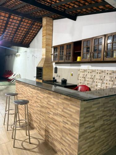 a kitchen with a counter and two bar stools at Casa 3km da praia com piscina, 3 quartos, 2 km das praia do Aracagir in São Luís