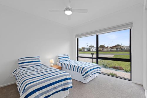 twee bedden in een kamer met een groot raam bij Mercer on Port in Portarlington
