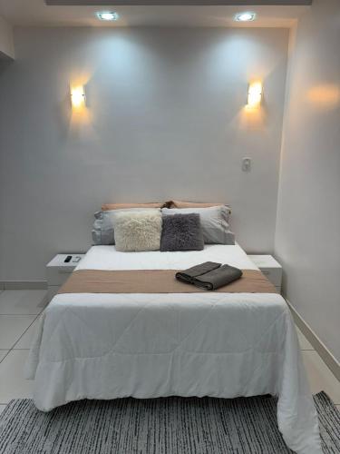 a bedroom with a large white bed with two lights at refugio pe na areia in Rio de Janeiro