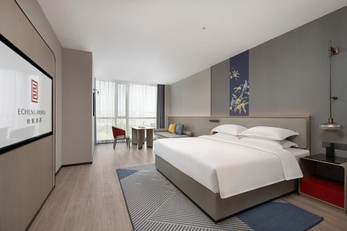 a bedroom with a large white bed and a living room at Hefei High-Speed Railway South Station North Square Yicheng Hotel in Hefei